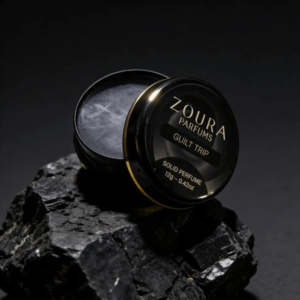 Zoura Guilt Trip Solid Perfume open jar on black rock