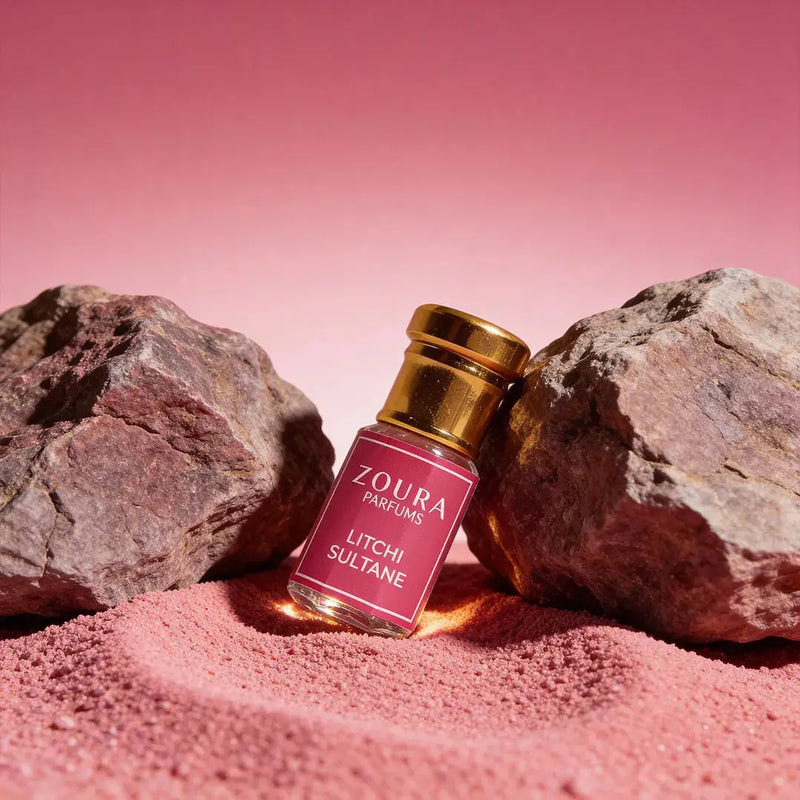 Zoura Parfums Litchi Sultane Attar bottle on pink sand with rocks – long lasting unisex attar