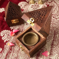 Wooden incense burner with a gold interior on a patterned fabric background