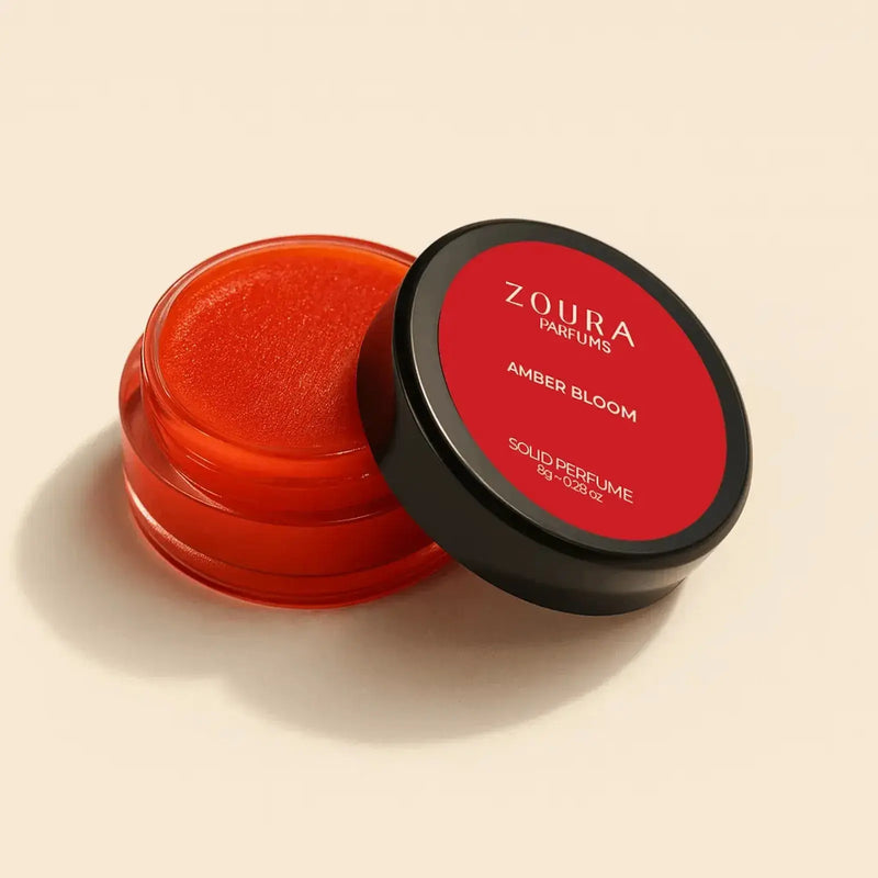 Open jar of Zoura Amber Bloom Unisex Solid Perfume showing orange balm texture, 8g