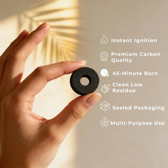 Hand holding a round Zoura quick-lighting charcoal tablet for bakhoor