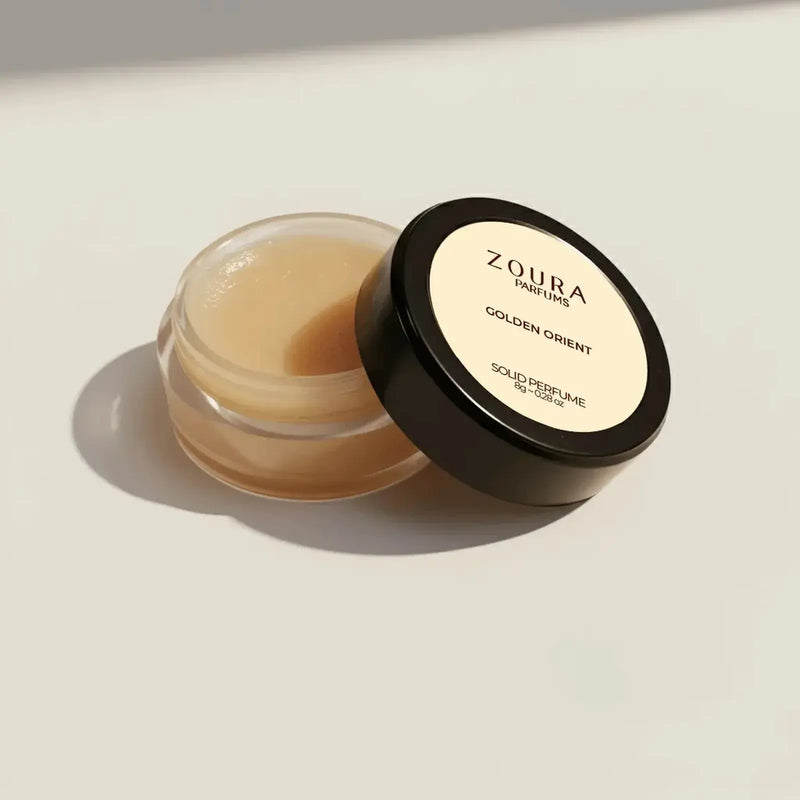 Open jar of Zoura Golden Orient Unisex Solid Perfume showing golden balm texture, 8g