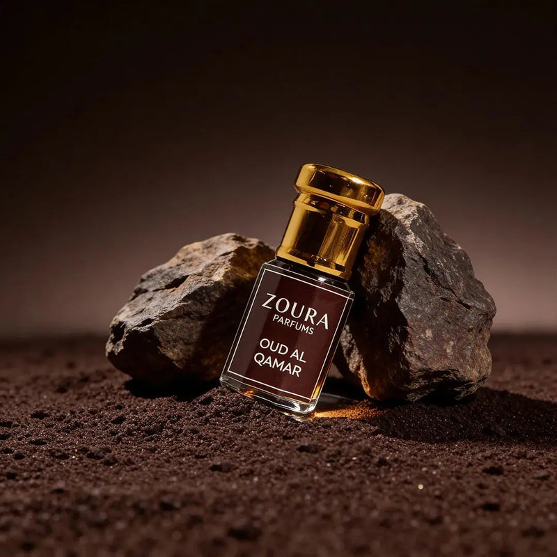 Zoura Parfums Oud Al Qamar oud attar bottle styled with rocks in warm desert-inspired lighting
