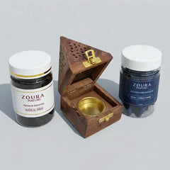Two Zoura Perfumes products and a wooden bakhoor burner on a light gray background